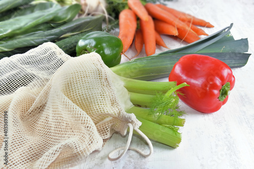 close on vegetables in a reusable  bag  and other  fresh vegetables  on a whi...