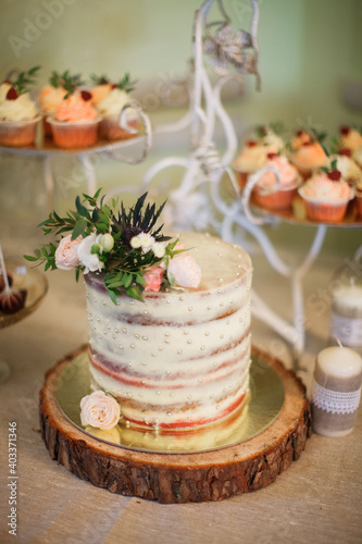 Wedding cake with fresh flowers. Confectionery art. Candy bar. Cupcakes with fresh berries.