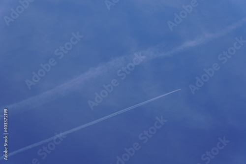  Photo of jet steam and carbon footprint made by commercial planes. Beautiful blue sky on a clear sunny day. Background.