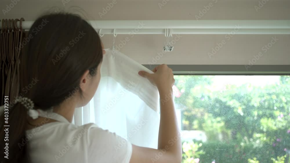 Asian woman installing curtain by herself at home, DIY concept. Asian woman installing curtain by herself at home, DIY concept.