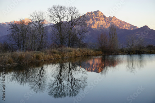 mirror reflection of the mountains at dusk in a pond above Serre Ponçon lake, France with the sun setting