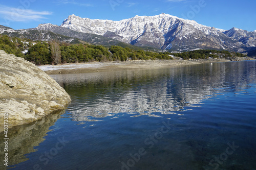 mirror reflection of the mountains in Serre Ponçon lake, France on a cold winter day