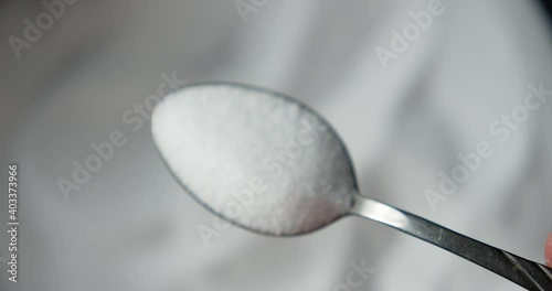 The man's hand takes a spoonful of salt. 