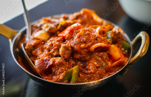 Kadai Mushroom, a delicious dish made of sautéed button mushrooms, onions, bell peppers in a spicy, tangy tomato gravy, served in a small wok pan.