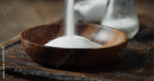 Salt is poured into a wooden plate. 