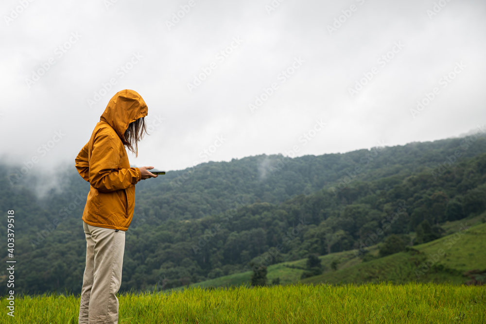 woman hand holding smartphone standing in the mountains with nature background. Teenager hiking travel in rural area lost signal phone.