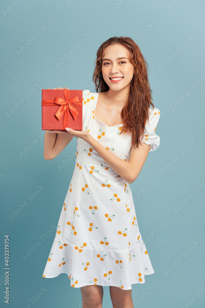 Portrait of an excited young girl holding present box isolated over blue background. Portrait of an excited young girl holding present box isolated over blue background.
