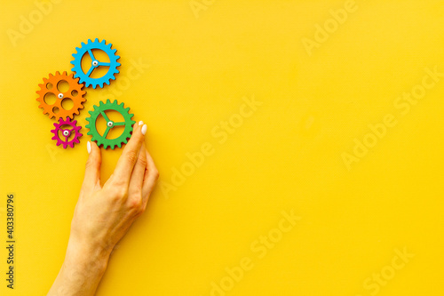 Teamwork concept. Hand connecting gears into puzzle - symbol of working mechanism