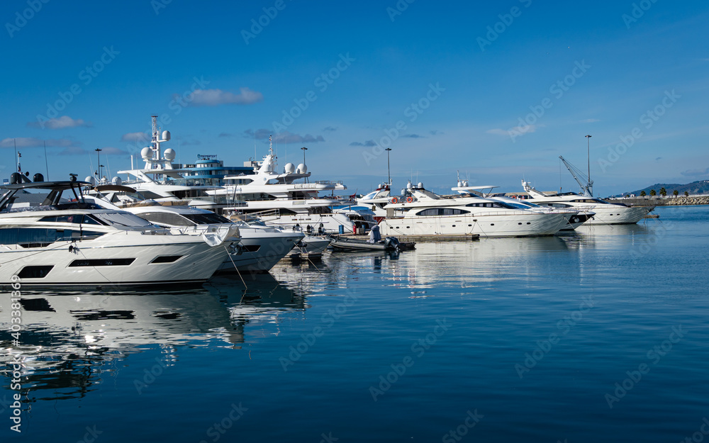 Sochi, Russia - November 23, 2020: Sochi Commercial Sea Port. Motor ships and yachts at the pier in front of main building of Marine Station. Close-up. Calm Black Sea.