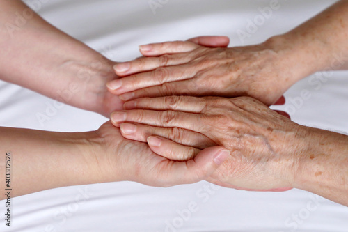 Wrinkled hands of senior woman in the palms of a young woman. Concept of care and support, elderly mother and daughter