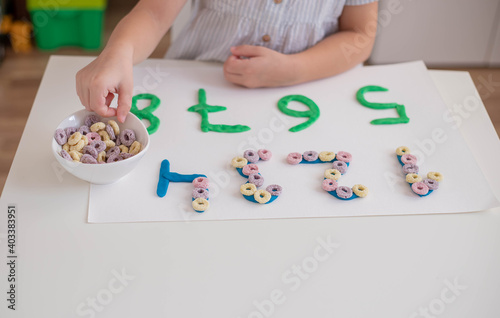 Child practice motor skills, make a numbers with play dough. Home education.
