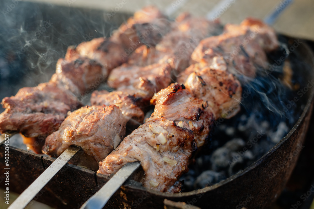 Grilling marinated shashlik preparing on a barbecue grill over charcoal.  Shashlik is a form of Shish kebab popular in Eastern Europe. Shashlyk (meaning  skewered meat) was originally made of lamb. Stock Photo