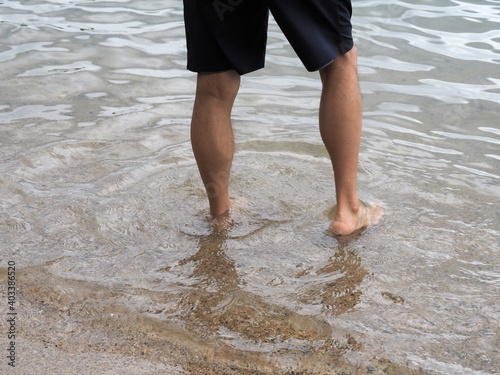 素足で海岸に立つ男性の脚 © poteco