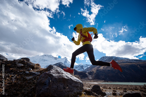 Woman trail runner cross country running in high altitude winter mountains