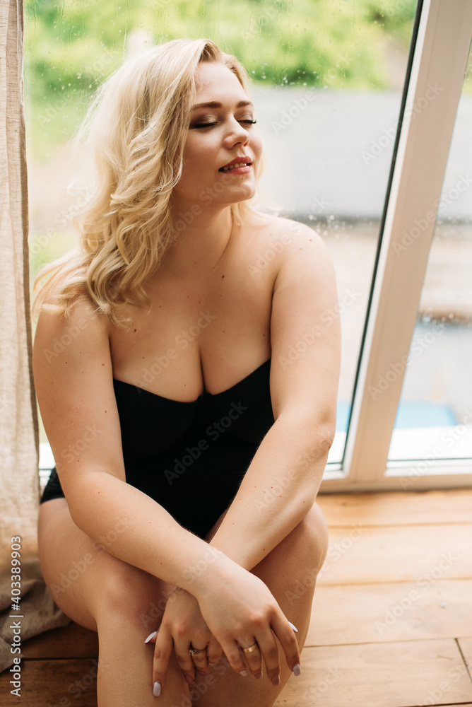 Young beautiful blonde plus size model in shapewear, xxl woman on gray studio background, full length portrait