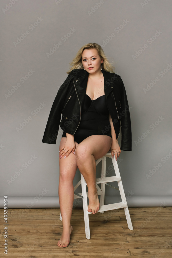 Young beautiful blonde plus size model in shapewear, xxl woman on gray  studio background, full length portrait Stock Photo