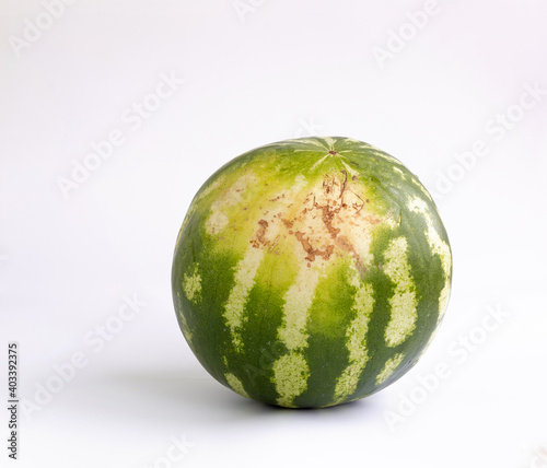 Whole watermelon isolated on white background. The part that was lying on the ground during maturation.
