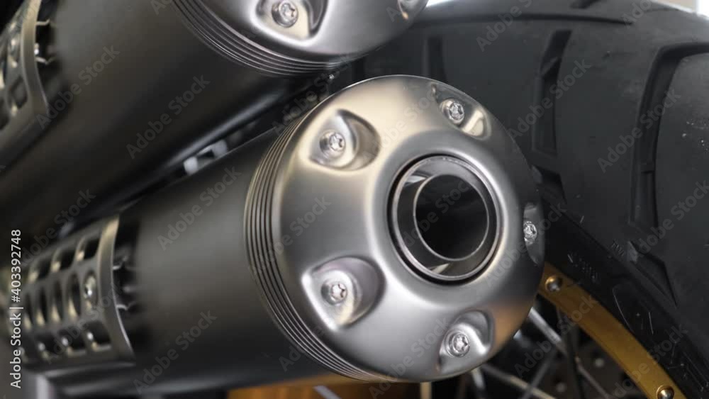 Matte silver exhaust pipe of the new modern motorcycle at the dealer showroom. Closeup cinematic shot. Matte silver exhaust pipe of the new modern motorcycle at the dealer showroom. Closeup cinematic shot.
