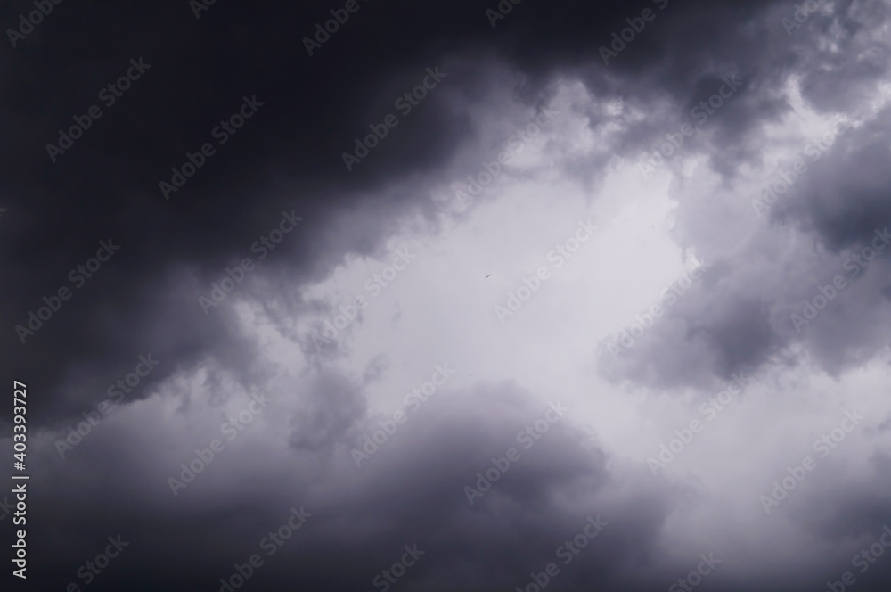 Obraz premium Dark gray storm clouds and a bird flying away into the distance.