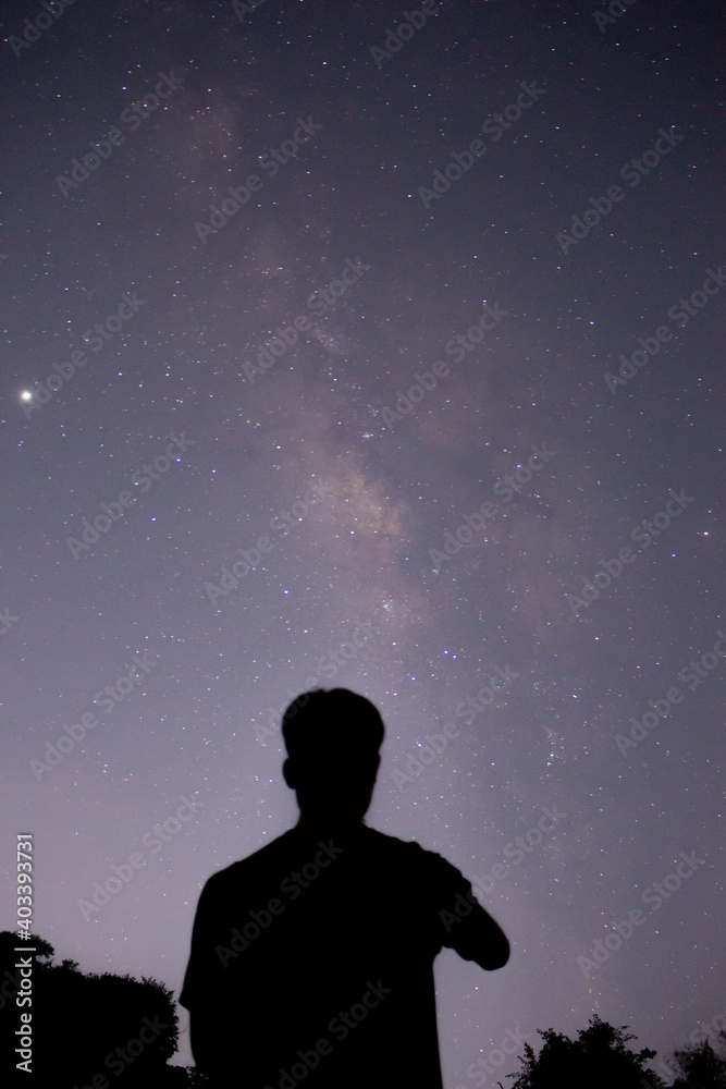 the man standing in front of the sky with the beautiful milky way