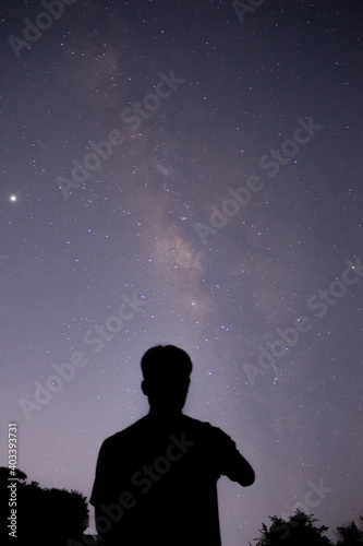 the man standing in front of the sky with the beautiful milky way