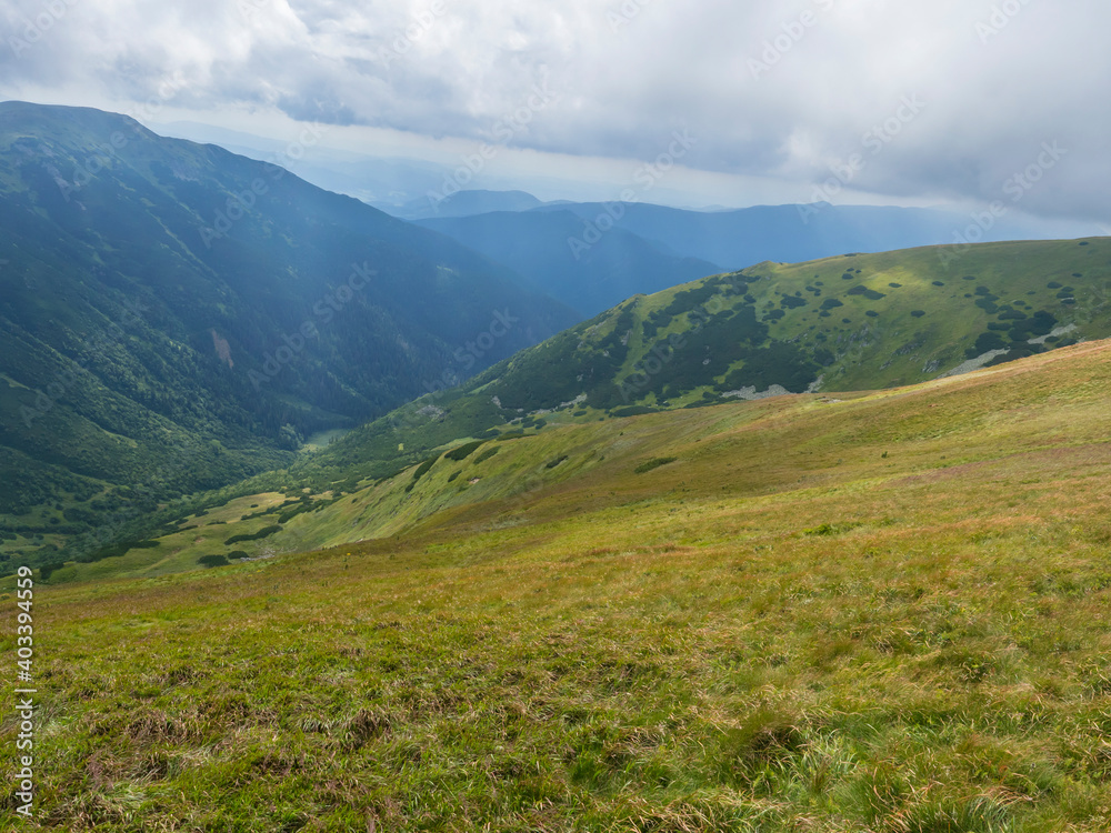 View from grassy hill slopes of hiking trail from Chopok at mountain meadow landscape of ridge Low Tatras mountains Nature park, Slovakia. cloudy late summer day