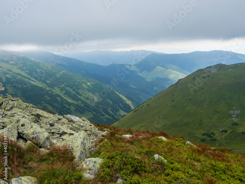 View from grassy hill slopes of hiking trail from Chopok at mountain meadow ridge Low Tatras mountains, Slovakia. Fog and clouds, late summer day