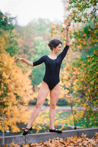 Beautiful female  ballerina  athlete in black bodysuit training in the park
