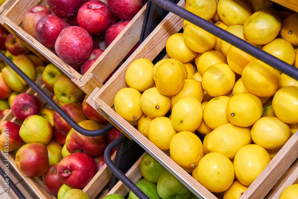 Lemons, red and green apples in wooden boxes on store shelves