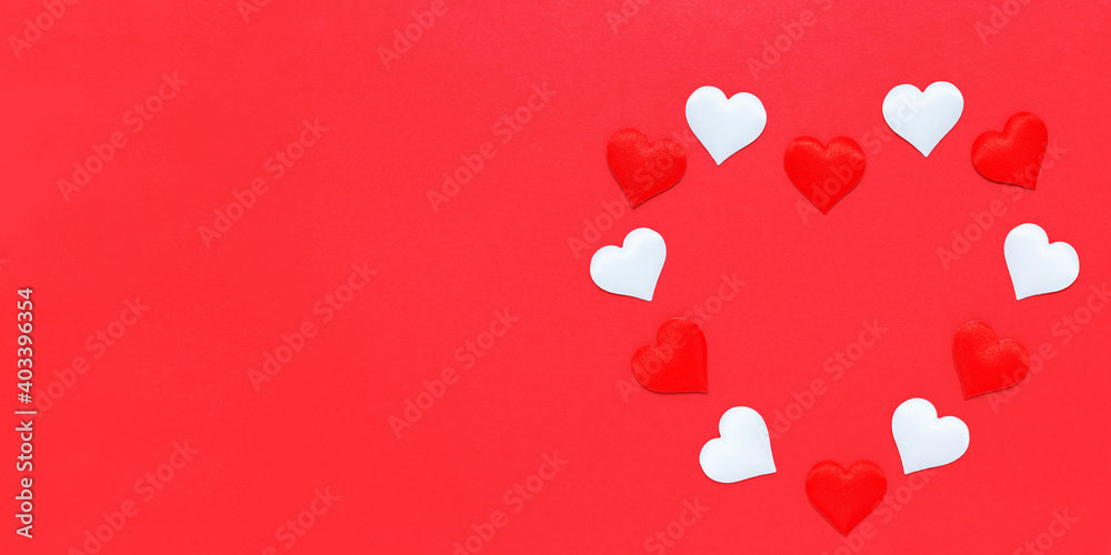 Decorative small red and white hearts are laid out in the shape of a large heart on a red background. Valentine's day texture. Love concept. Flat lay. Banner