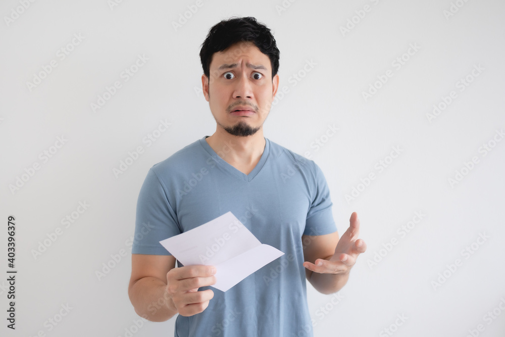 Asian man is sad and shocked by the letter in his hand on isolated background. Asian man is sad and shocked by the letter in his hand on isolated background.