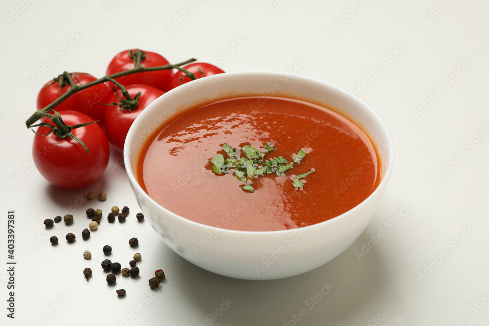 Bowl with tomato soup and ingredients on white background