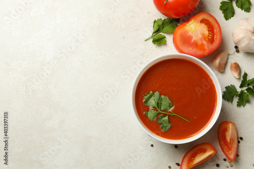 Bowl with tomato soup and ingredients on light background
