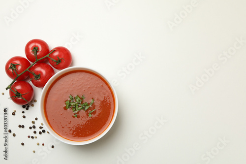 Bowl with tomato soup and ingredients on white background