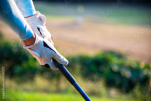Close up Hand asian woman putting golf ball on tee with club in golf course on sunny day for healthy sport. Lifestyle Concept.