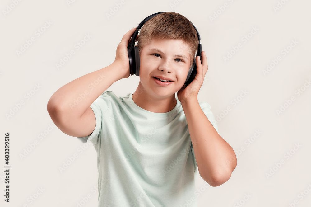 Portrait of happy disabled boy with Down syndrome in headphones listening to music and looking at camera while posing isolated over white background Portrait of happy disabled boy with Down syndrome in headphones listening to music and looking at camera while posing isolated over white background