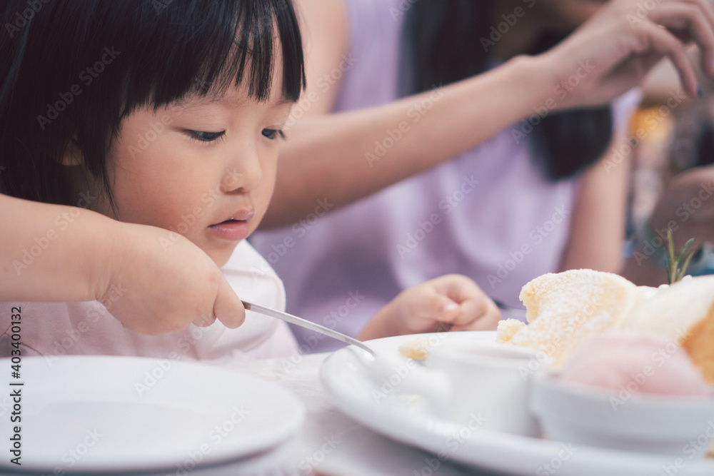 Asain cute girl eat dessert pancake with spoon. Concept for kid and family lifestyle.