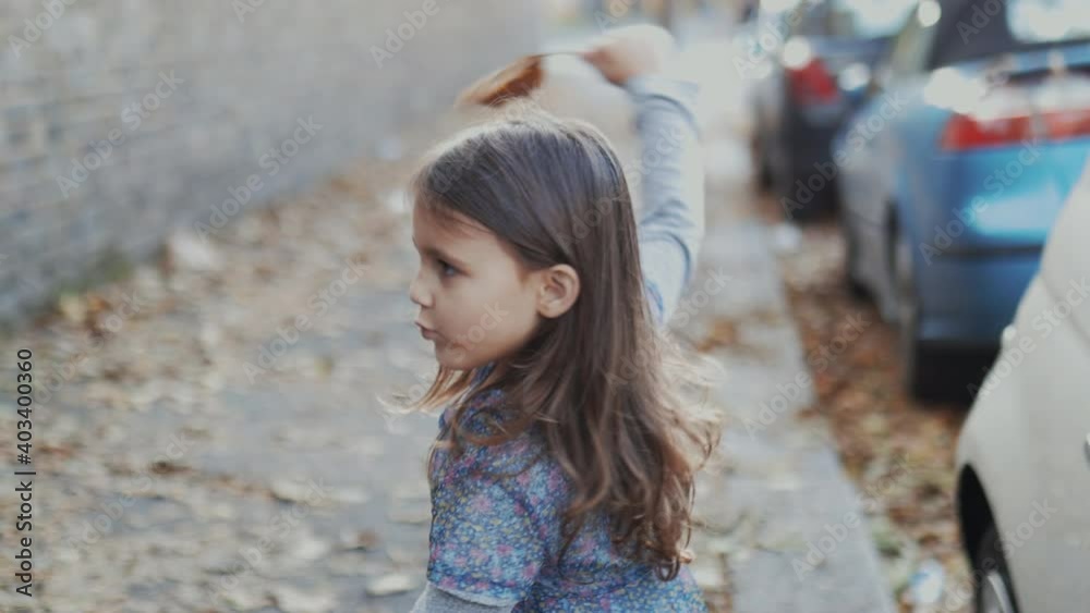 Happy little girl playing around in an autumn street Happy little girl playing around in an autumn street