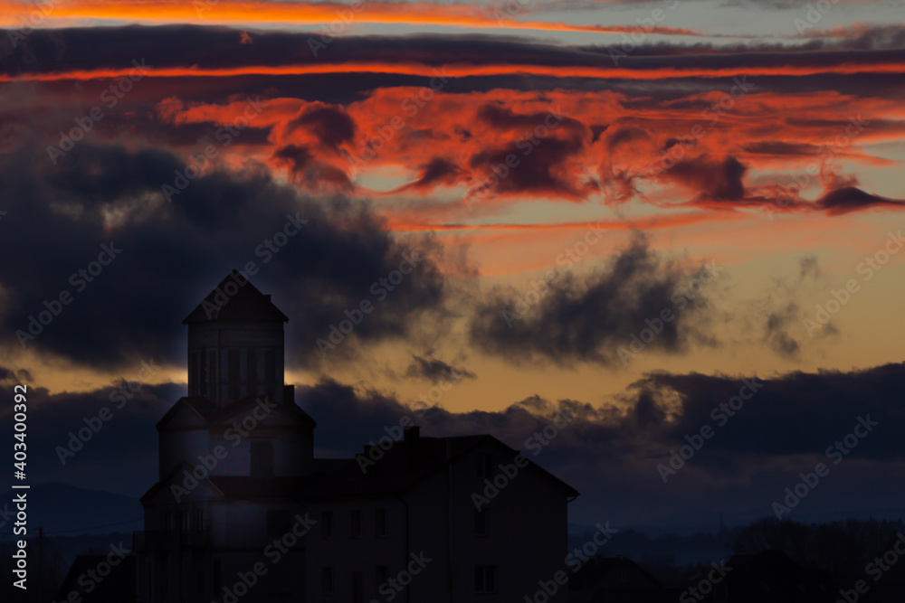 landscape of a small castle on a background of sky with unusual clouds of rich colors during sunset