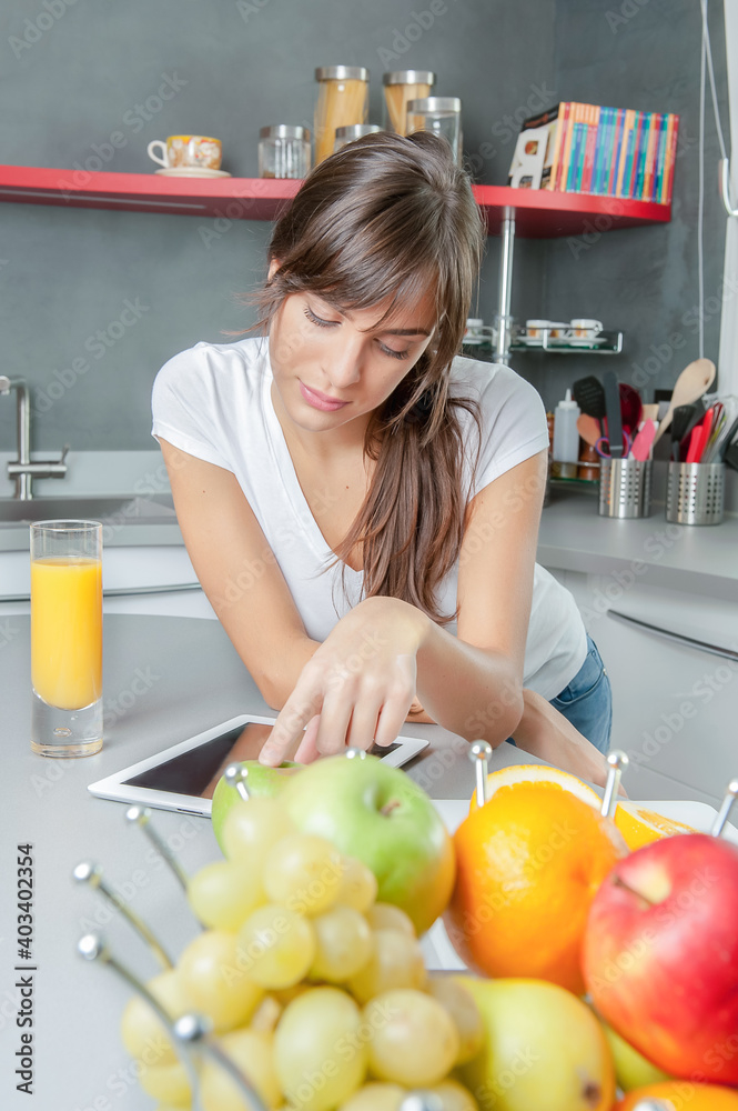 Young smiling woman with fruits in a modern kitchen