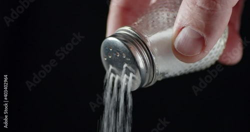The man's hand holds a jar of salt. 