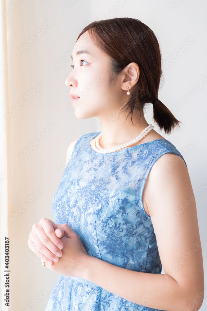 窓の前に立つドレスを着た女性
