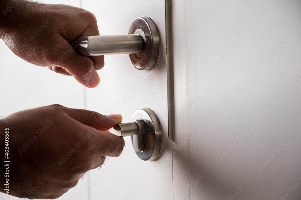 A man's hand was grasping the handle to open the door. He unlocked the door to enter the room. A man's hand was grasping the handle to open the door. He unlocked the door to enter the room.