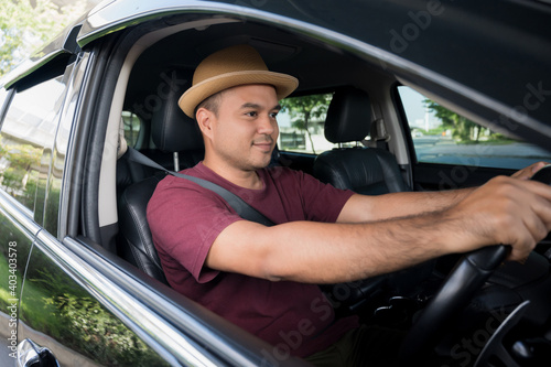 Young asian man wearing hat and driving car.