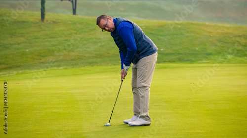 Close-up of a golf player who with a putt pocket the ball on the green