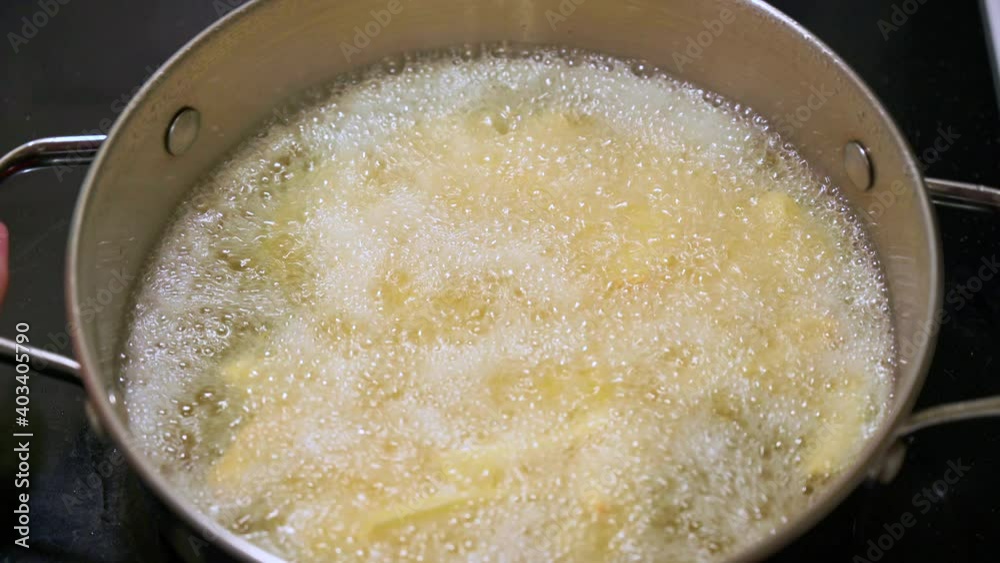 Round deep fryer on stove top bubbling with vegetable oil Round deep fryer on stove top bubbling with vegetable oil