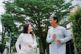 Cheerful asian senior couple jogging exercising outdoors at park.
