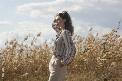 Outdoor fashion portrait of Caucasian woman in wide leg beige pants and patterned blouse.