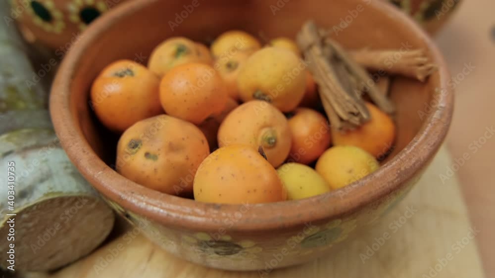 Fresh Mexican hawthorns and cinnamon sticks in a clay bowl Fresh Mexican hawthorns and cinnamon sticks in a clay bowl