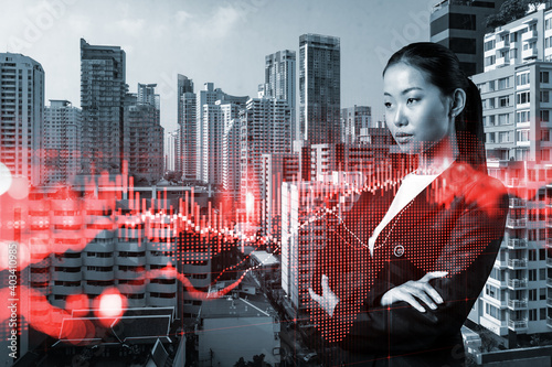 Attractive young Asian trader and stock market analyst in suit dreaming about market behavior and forecast in crisis. Women in business concept. Forex chart. Bangkok. Double exposure.